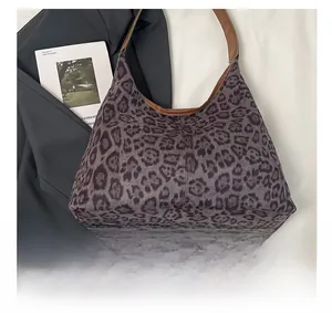 Detail of leopard print tote bag with brown leather handles on grey suit and magazine