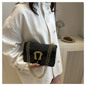 Detailed shot of a black leather chain bag with gold horseshoe buckle and M pattern