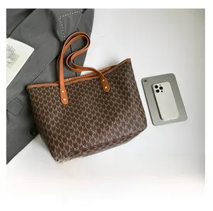 Detailed view of monogram tote bag capacity next to a smartphone for size reference