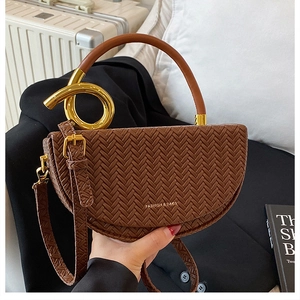 Brown woven saddle bag with gold ring handle and shoulder strap in lifestyle setting