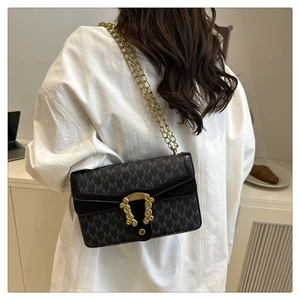 Detail of a vintage black chain bag with M-pattern and retro gold floral clasp