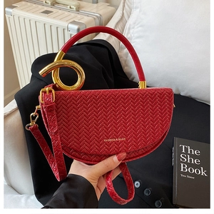 Detail of red crescent bag featuring woven leather texture and golden metal hardware