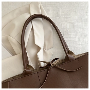 Detailansicht der braunen Leder-Tote-Bag mit großem Webmuster und Schleifenakzent