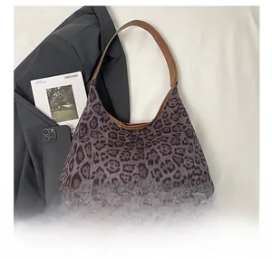 Detail of leopard print tote bag with brown leather handles and textured fabric