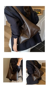 Detail view of large dark brown leather hobo bag with smooth oily texture and wide strap