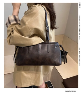 Detail of deep brown shoulder bag with decorative stitching and adjustable metallic buckle