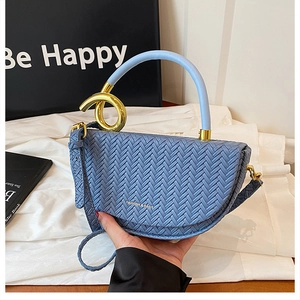 Close-up of a light blue woven texture saddle bag with gold metal clasp and top handle
