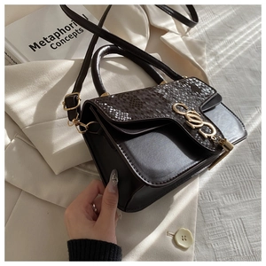 Detail of dark brown faux crocodile texture handbag with elegant gold metal buckle