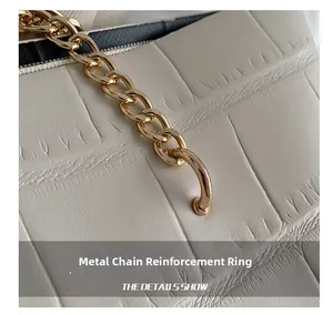 Close-up of golden chain hardware and crocodile texture on cream shoulder bag