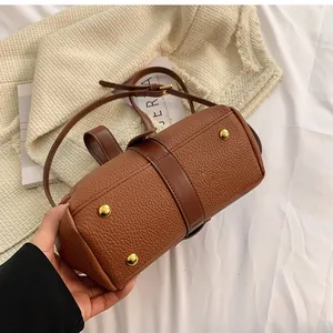 Detail of brown lychee leather handbag base featuring four gold protective metal feet