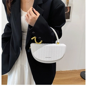 Chic white woven saddle bag with gold ring handle worn with elegant fashion outfit