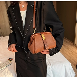 Close-up of a vintage brown pebble leather doctor bag with a gold metal frame and clasp