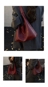 Macro shot of burgundy vintage hobo bag texture and wide strap detail on dark pavement