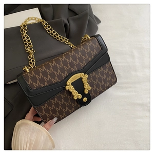 Close-up of vintage brown and black crossbody bag with M-print and golden engraved buckle