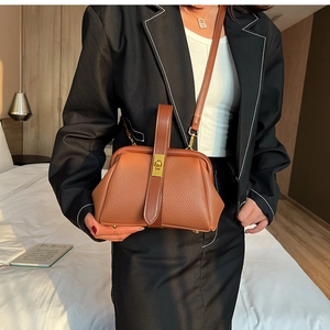 Detailed view of caramel leather satchel with metal frame closure and shoulder strap