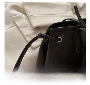 Detail of dark brown leather tote featuring drawstring tassels and silver metal eyelets