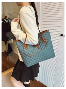 Detail of teal quilted tote bag with brown PU leather straps and fashion label tag