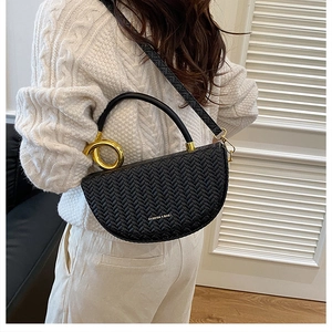 Detail of black woven saddle bag with gold metal handle and logo on model outfit