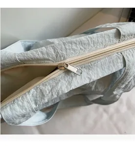 Détail de la fermeture éclair argentée sur un sac cabas en nylon bleu plissé
