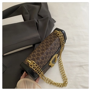 Close-up of vintage brown monogram bag with golden chain and textured flap lock detail