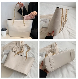 Detail view of white crocodile pattern tote bag with gold chain straps and bottom studs