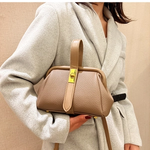 Detail of lychee textured leather satchel with golden clasp on light grey wool coat
