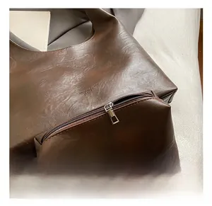 Close-up of deep brown leather tote set with embossed logo and metal zipper detail