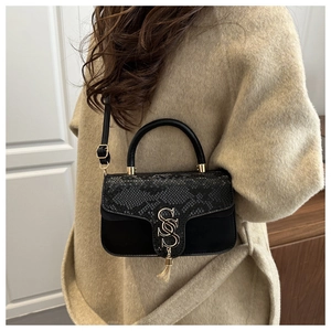 Detail of snake pattern flap and gold S-shaped buckle on black crossbody bag