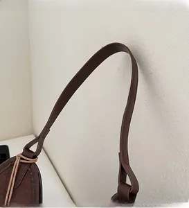 Detailed close-up of brown leather handles and premium suede stitching on the tote bag