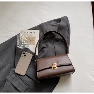 Detail of a brown minimalist baguette bag with a gold buckle on a stylish blazer