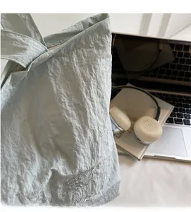 Détail du sac cabas en tissu froissé bleu clair avec broderie et texture douce