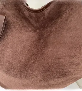 Close-up of deep brown suede fabric texture and leather edging on the tote bag