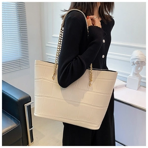Close-up of white crocodile embossed tote bag with elegant gold chain shoulder strap