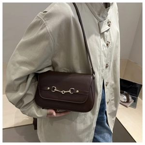 Detail view of dark brown leather shoulder bag with golden horsebit metal buckle hardware