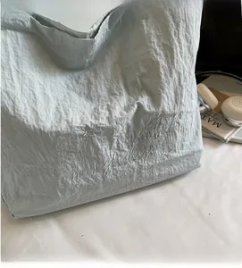 Détail du sac cabas plissé gris avec broderies délicates de cœurs et d'étoiles