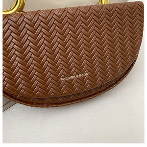 Detailed view of brown woven leather saddle bag with gold ring and fashion engraving