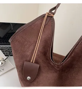 Close-up of brown suede tote bag featuring dark leather trim in a modern office setting