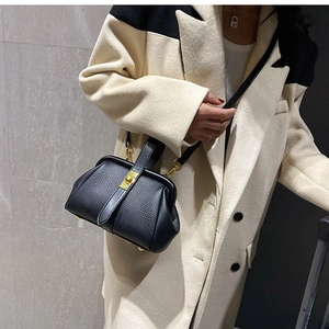 Detail of black pebbled leather doctor bag with gold clasp and adjustable strap