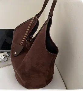 Detail of dark brown suede tote bag featuring leather straps and minimalist texture