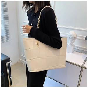 Detailed macro view of white crocodile pattern tote bag with gold metal chain strap
