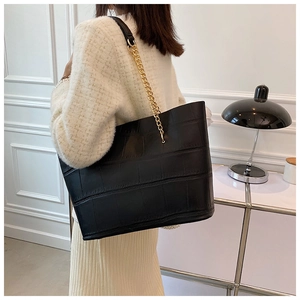 Detail view of black crocodile pattern tote bag with gold chain shoulder strap for women