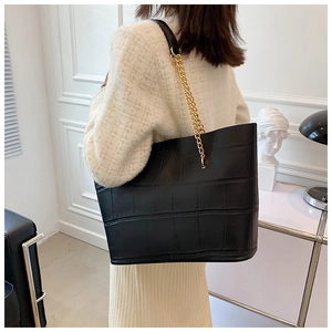 Close-up of black crocodile pattern tote bag with gold chain strap detail