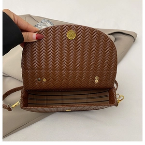 Detail view of woven brown leather saddle bag with striped lining and gold magnetic clasp