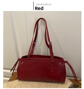 Detail view of red faux leather tote bag showing vertical stitching and drawstring accents