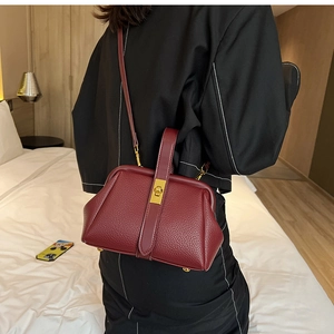 Detail of burgundy doctor bag with lychee texture leather and gold metal clasp hardware