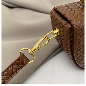 Detail of woven brown leather texture and premium gold metal hardware hooks on saddle bag