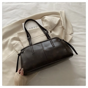 Detail of dark brown glossy leather tote with drawstrings and adjustable strap
