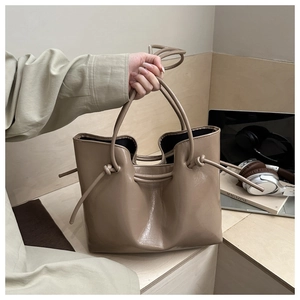Dettaglio della borsa tote beige trendy con nodo laterale e finitura lucida in stile urbano