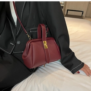 Detail of burgundy lychee leather doctor bag with gold twist lock and handle