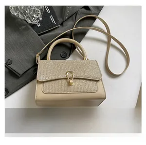 Close-up of beige crossbody bag with sparkling glitter flap and golden metal lock